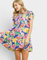 Woman wearing a colorful floral dress against a plain background