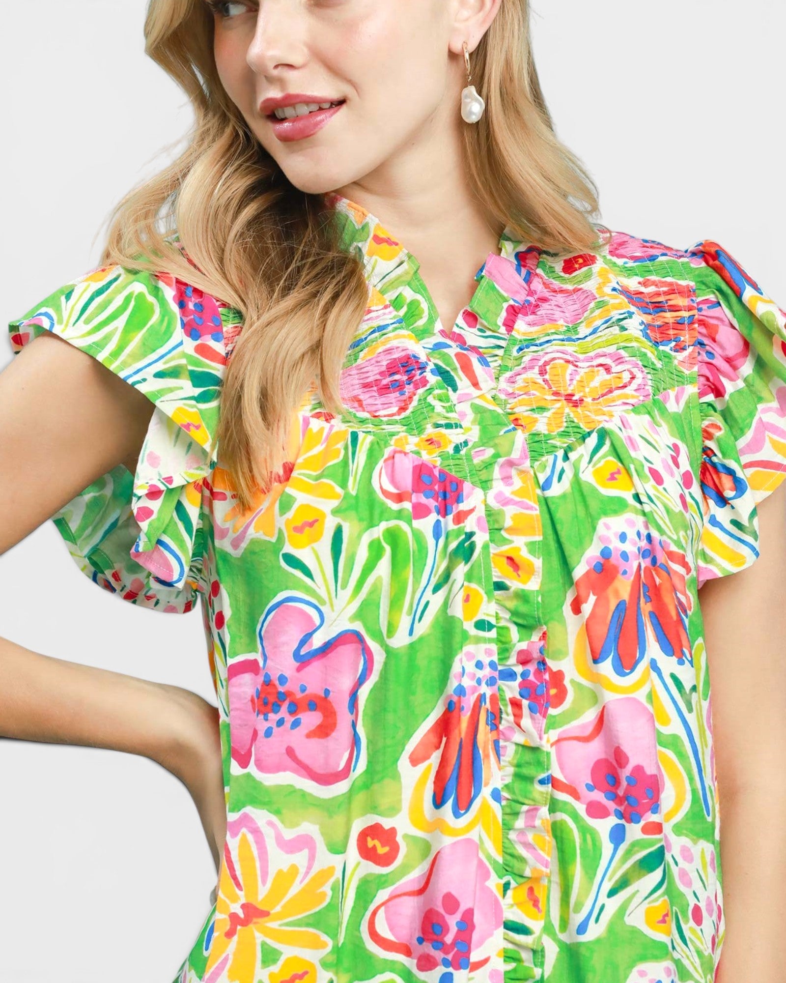 Woman wearing a colorful floral dress on a plain background