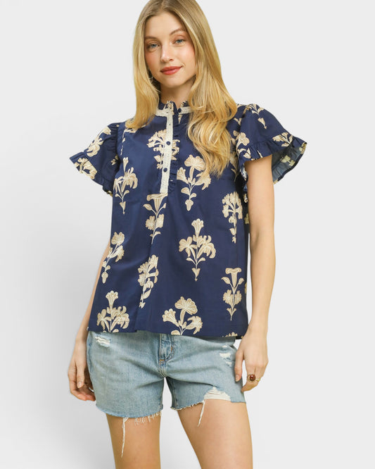 Woman wearing a navy floral blouse and denim shorts on a white background