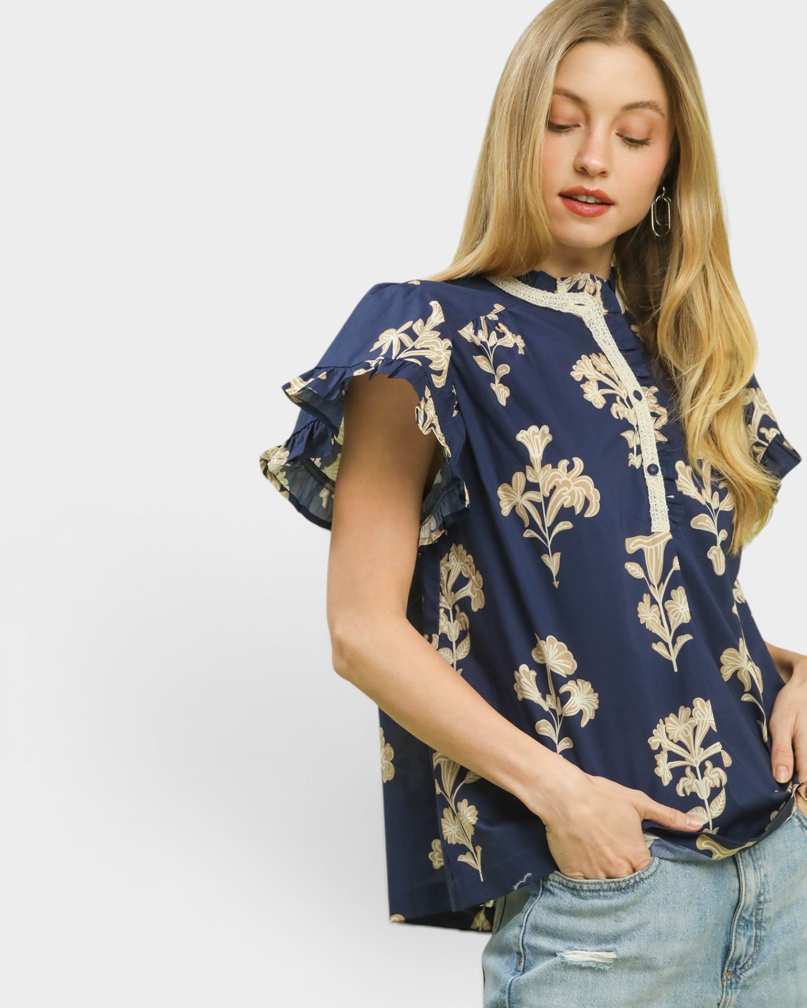 Woman wearing a navy blue blouse with floral patterns on a white background