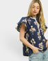 Woman wearing a navy blue blouse with floral patterns on a white background