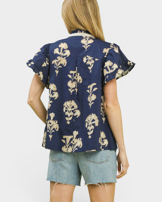 Woman wearing a navy blue floral patterned shirt and denim shorts on a white background