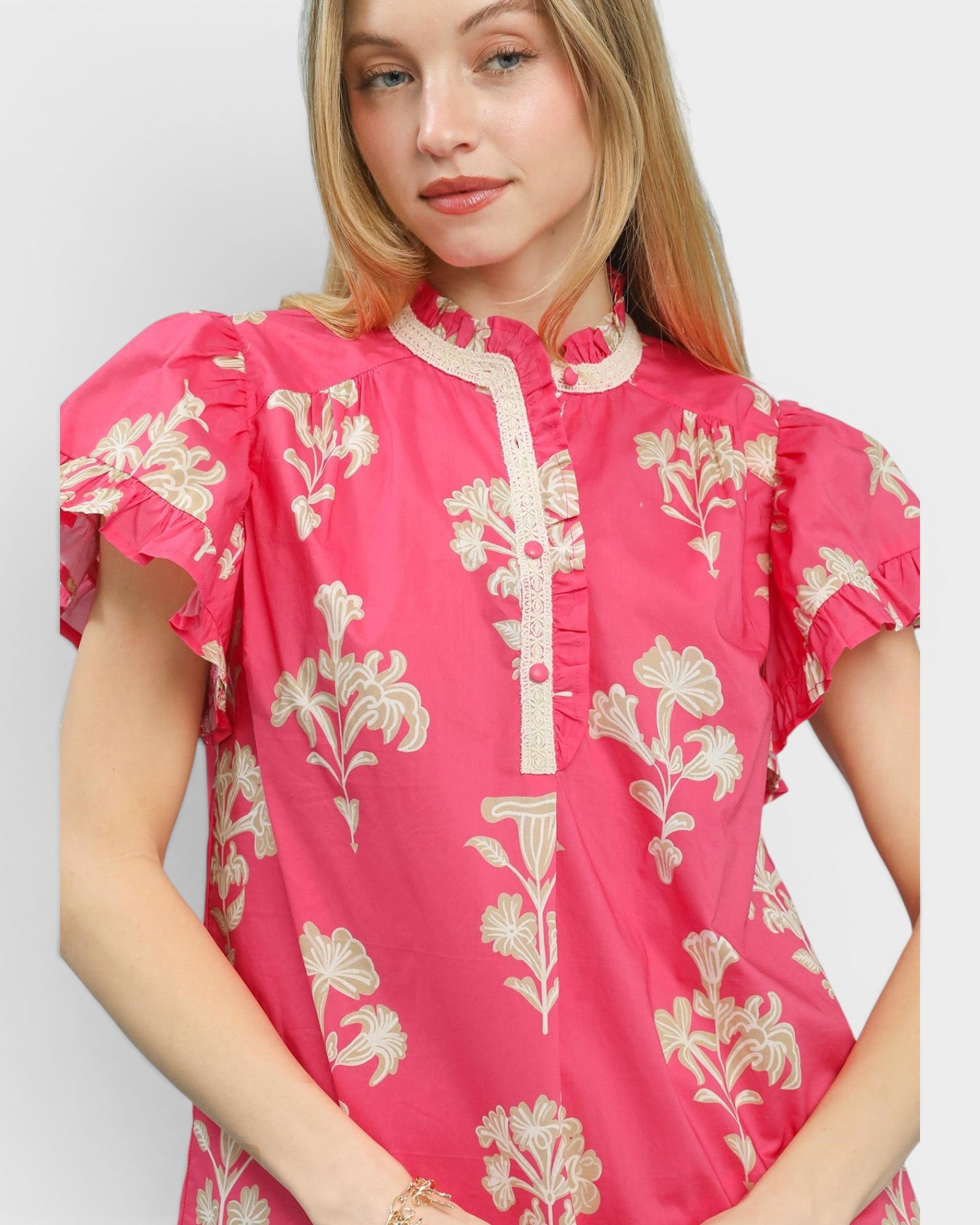 Woman wearing a pink floral blouse against a white background