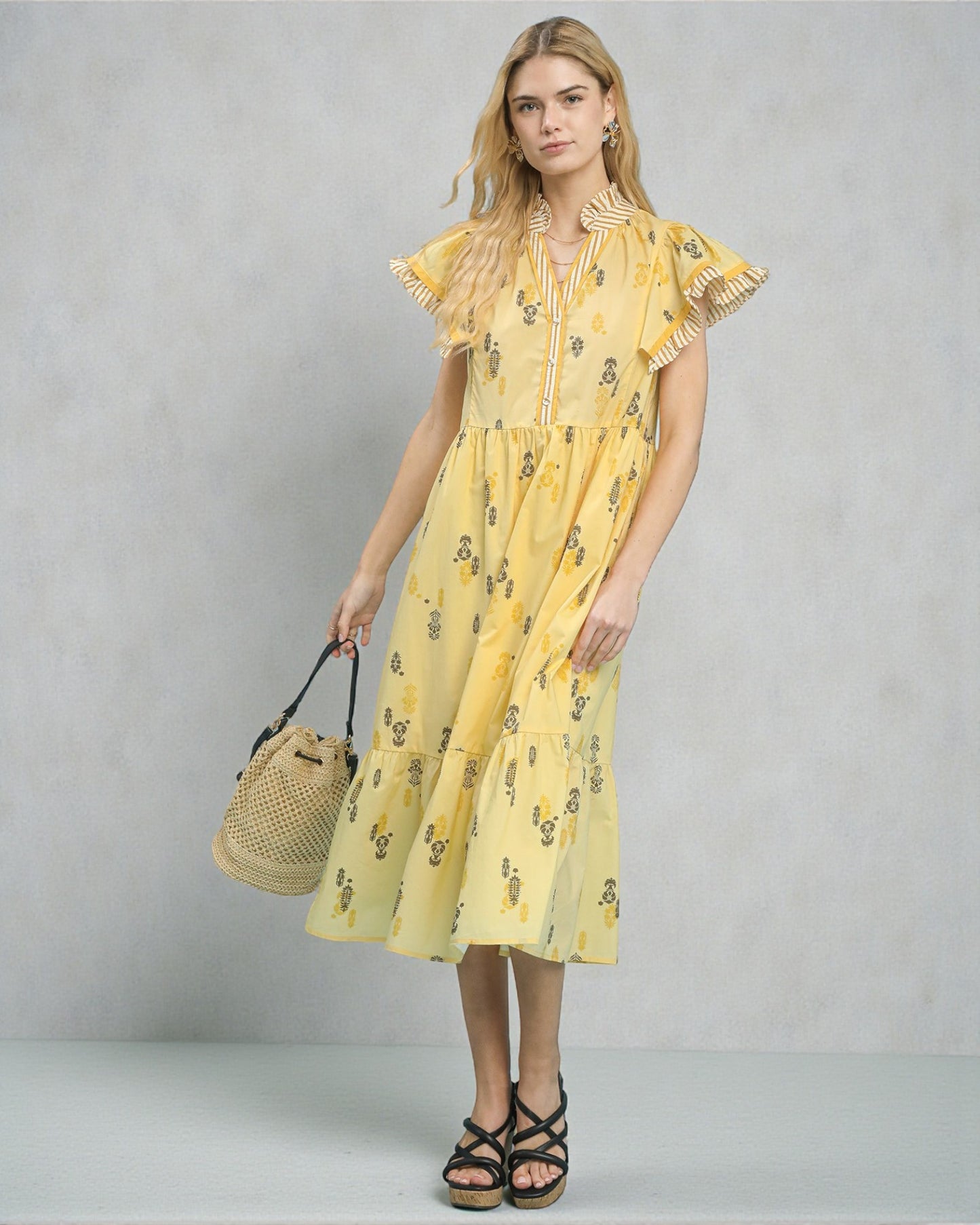 Woman wearing a yellow dress with a subtle pattern against a plain background