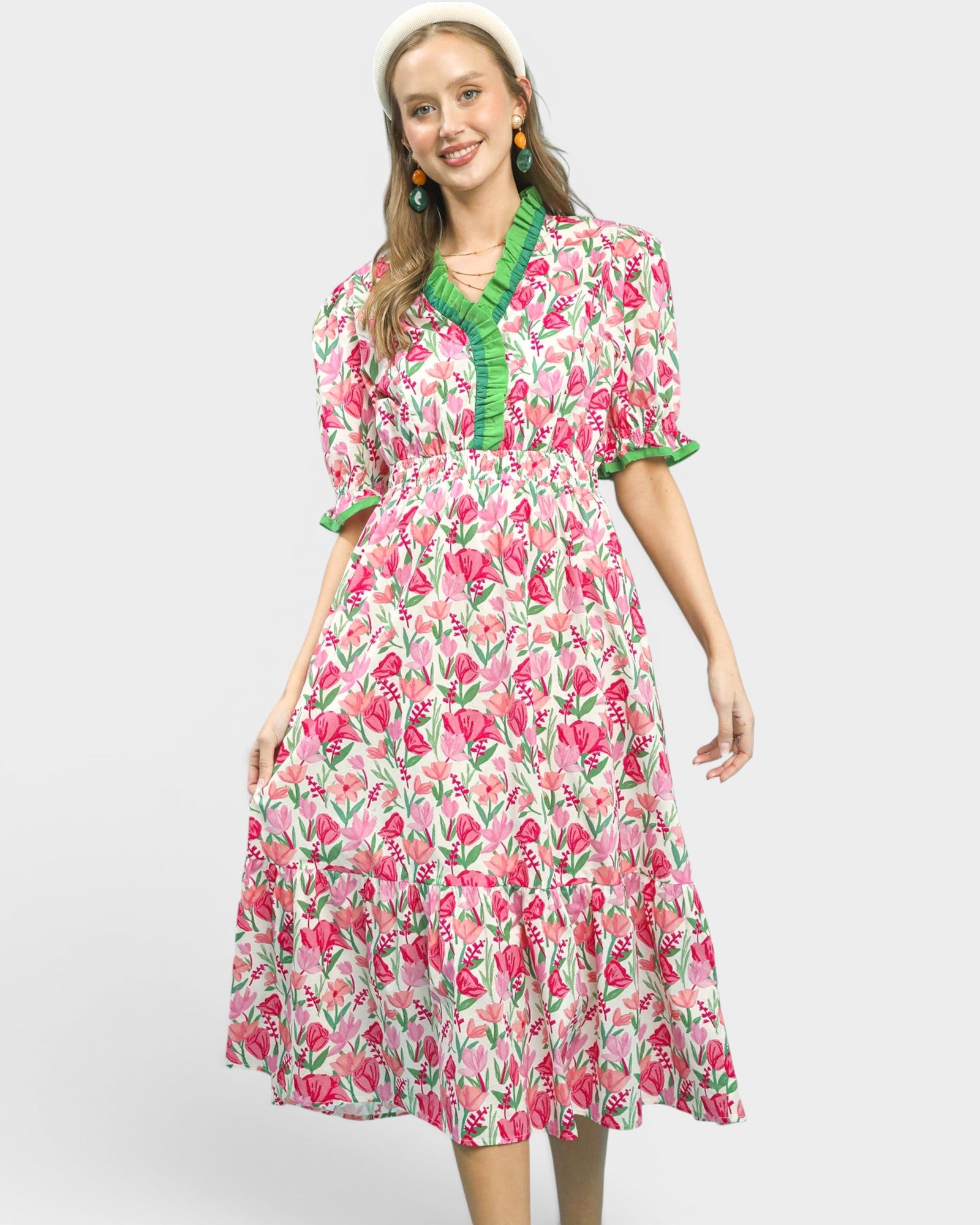 Woman wearing a floral dress with green trim on a white background