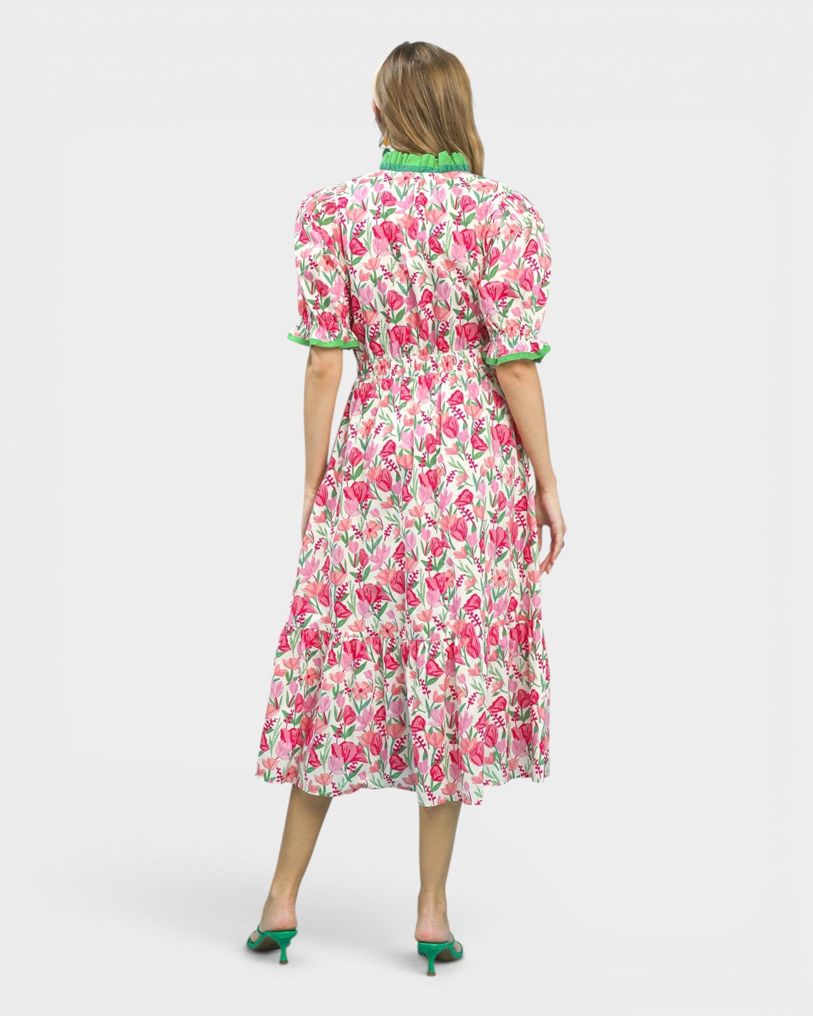 Woman wearing a floral dress with green trim on a white background