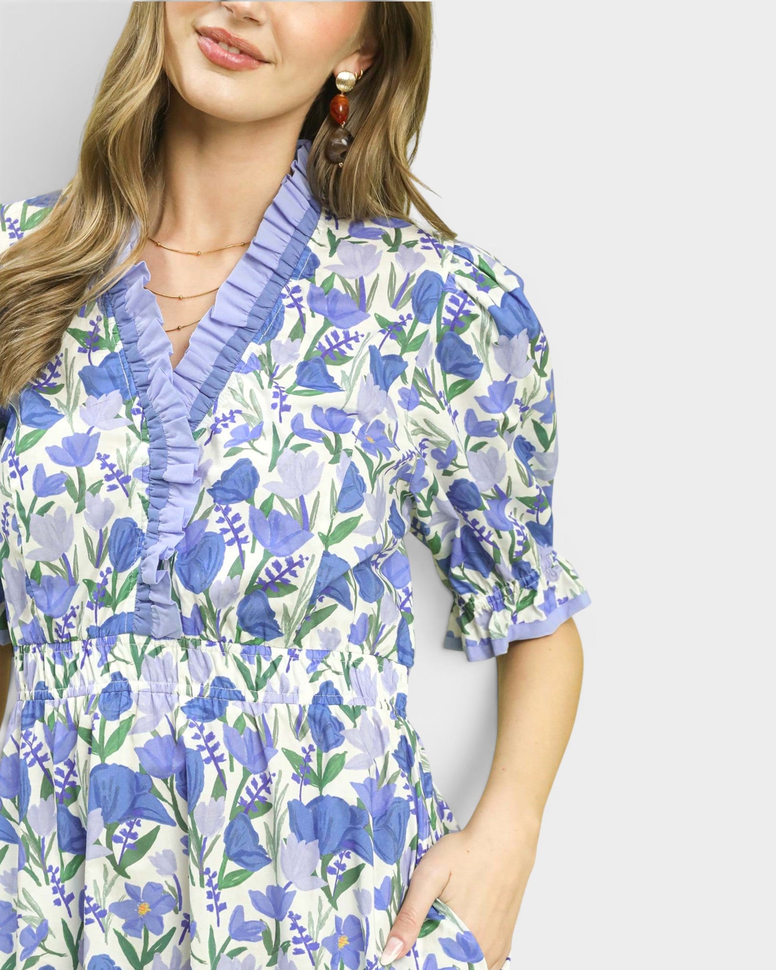 Woman wearing a floral dress with blue and purple flowers on a plain background