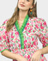 Woman wearing a floral dress with green trim on a plain background