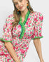 Woman wearing a floral dress with green accents on a plain background