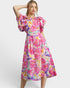 Woman wearing a colorful floral dress with ruffled sleeves on a white background