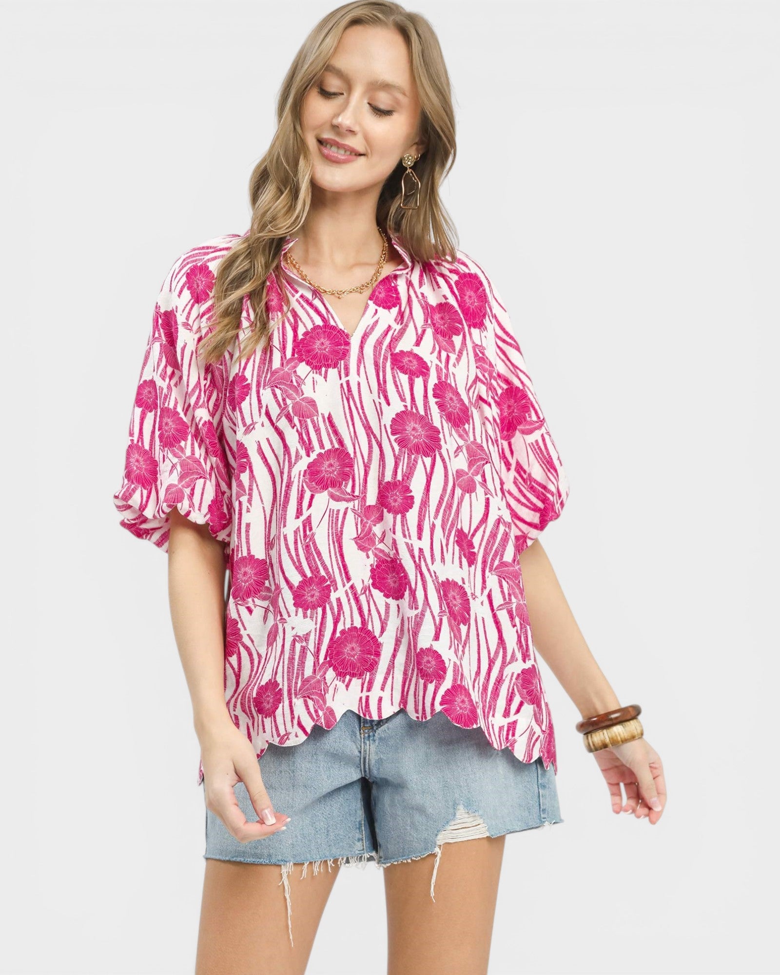 Woman wearing a pink floral blouse and denim shorts on a white background