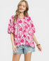 Woman wearing a pink floral blouse and denim shorts on a white background