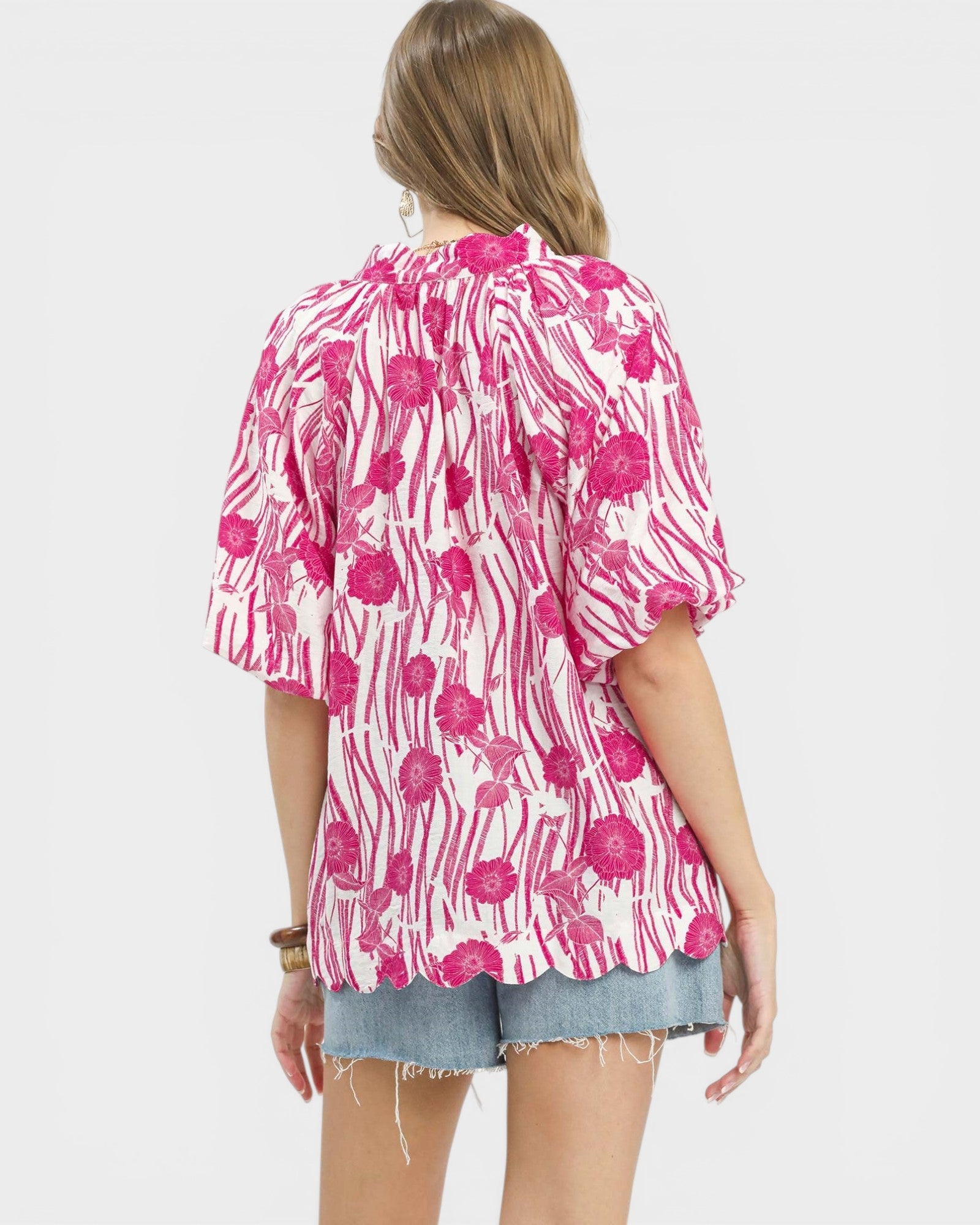 Woman wearing a pink floral kimono-style top on a white background