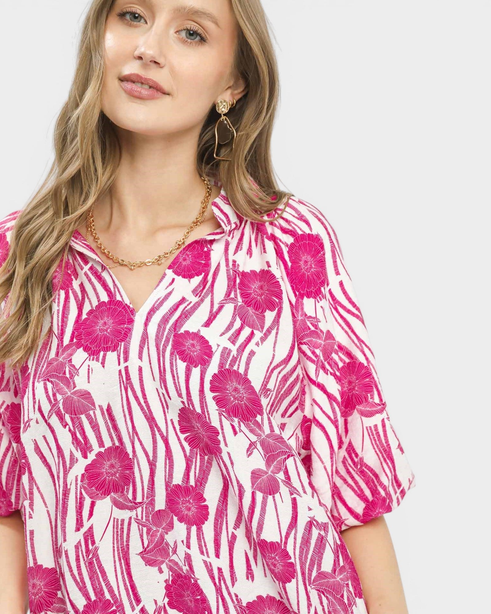 Woman wearing a pink and white floral blouse on a white background