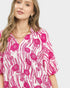 Woman wearing a pink and white floral blouse on a white background