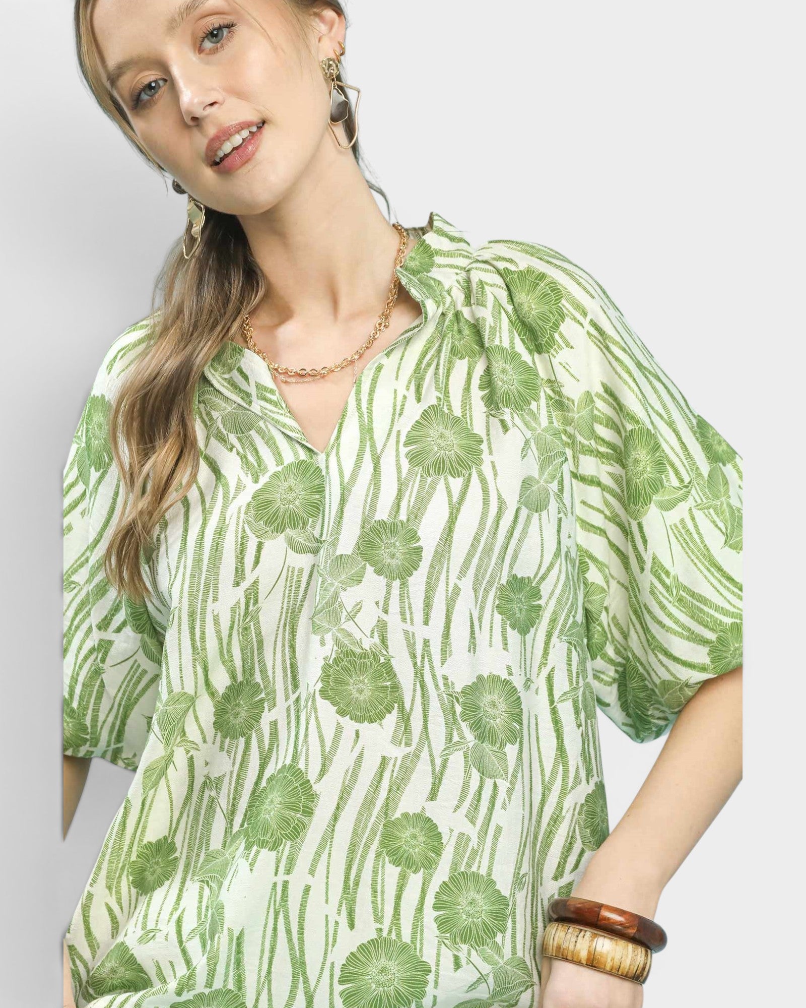 Woman wearing a green and white patterned shirt on a plain background
