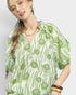 Woman wearing a green and white patterned shirt on a plain background