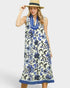 Woman wearing a sleeveless dress with blue floral pattern on a white background