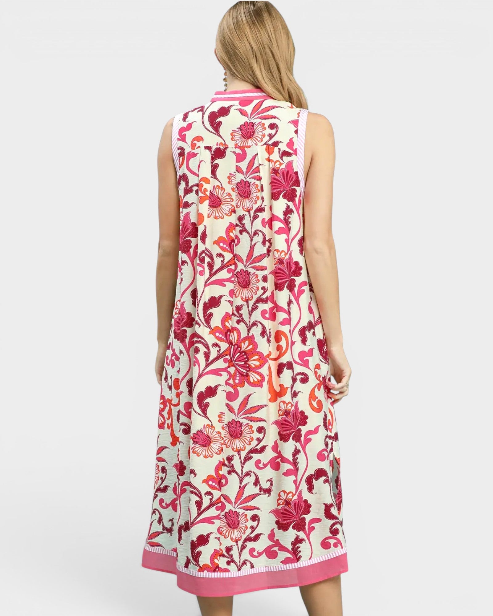 Woman wearing a sleeveless floral dress with pink and red patterns on a white background