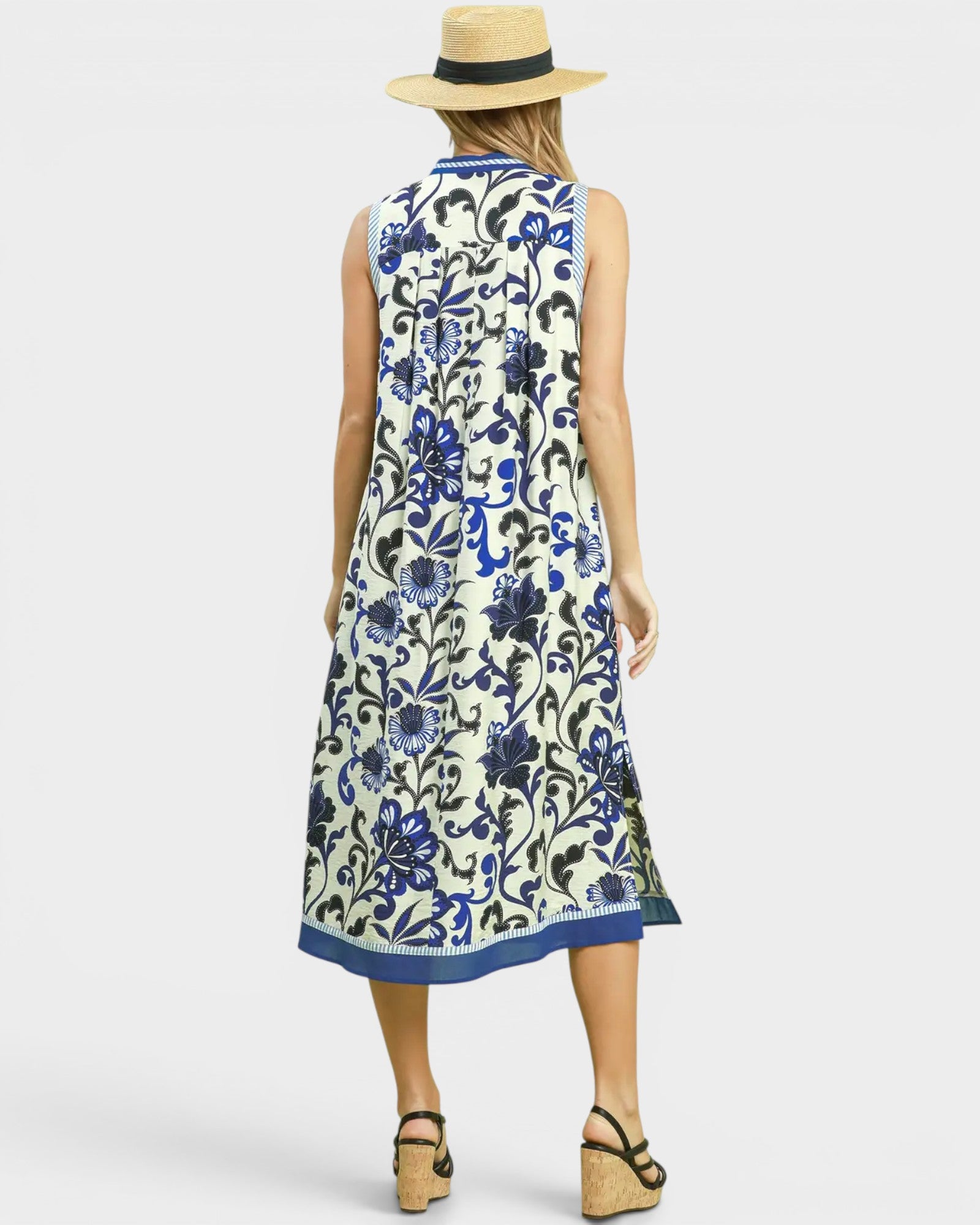 Woman wearing a sleeveless floral dress with blue patterns on a white background