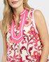 Woman wearing a sleeveless floral dress with pink and orange patterns on a white background