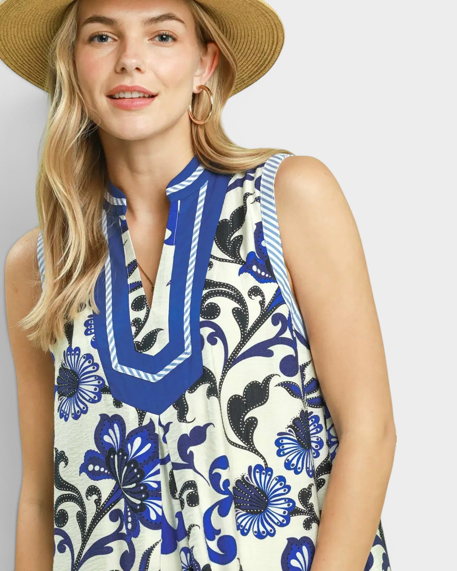 Woman wearing a sleeveless dress with blue floral pattern on a plain background