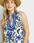 Woman wearing a sleeveless dress with blue floral pattern on a plain background