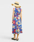 Person wearing a colorful floral dress and straw hat on a white background