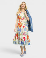 Woman wearing a colorful floral dress with a denim jacket on a white background