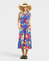 Woman wearing a colorful floral dress with a wide-brimmed hat on a white background