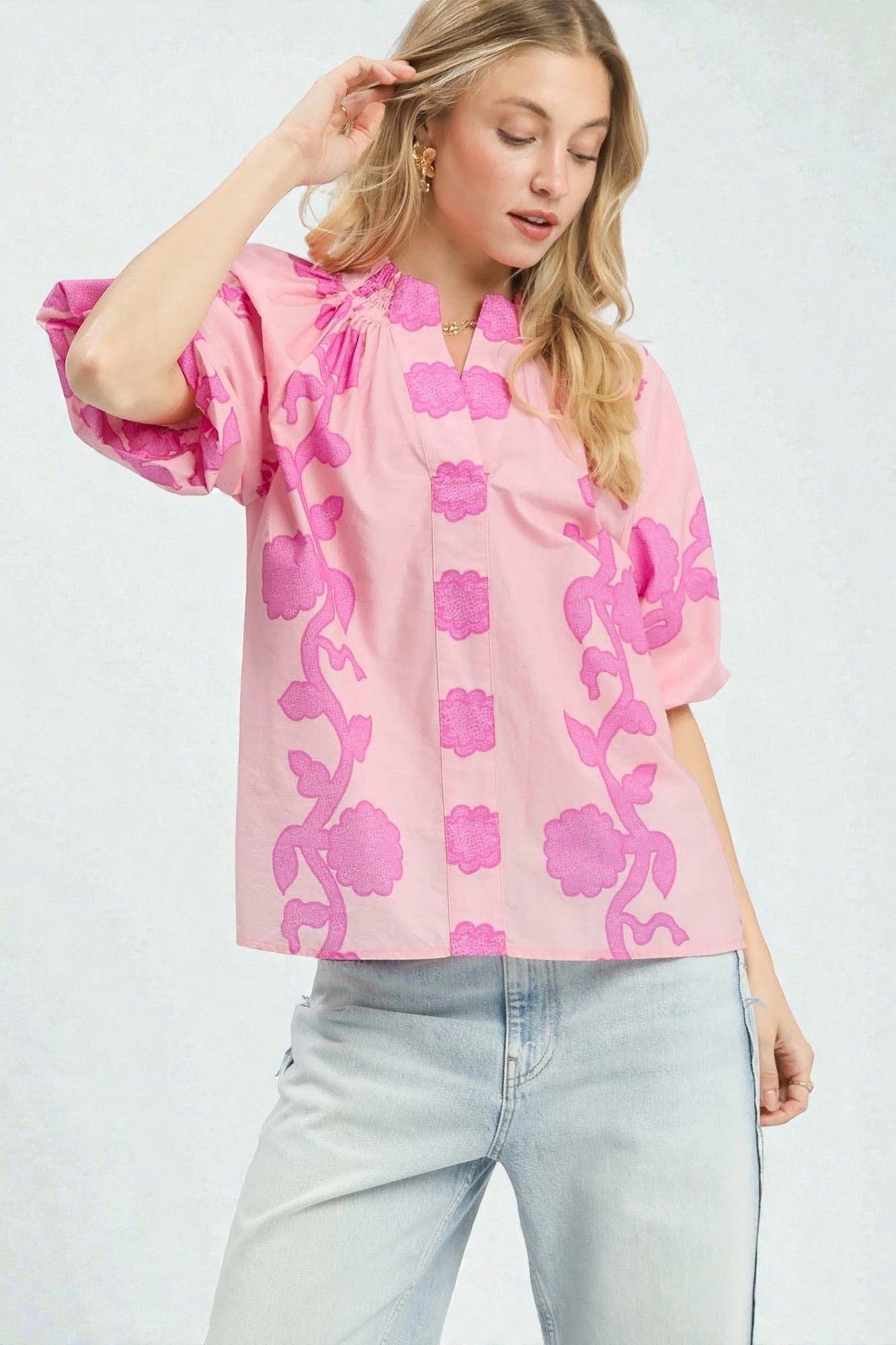 Woman wearing a pink floral blouse and light blue jeans on a white background