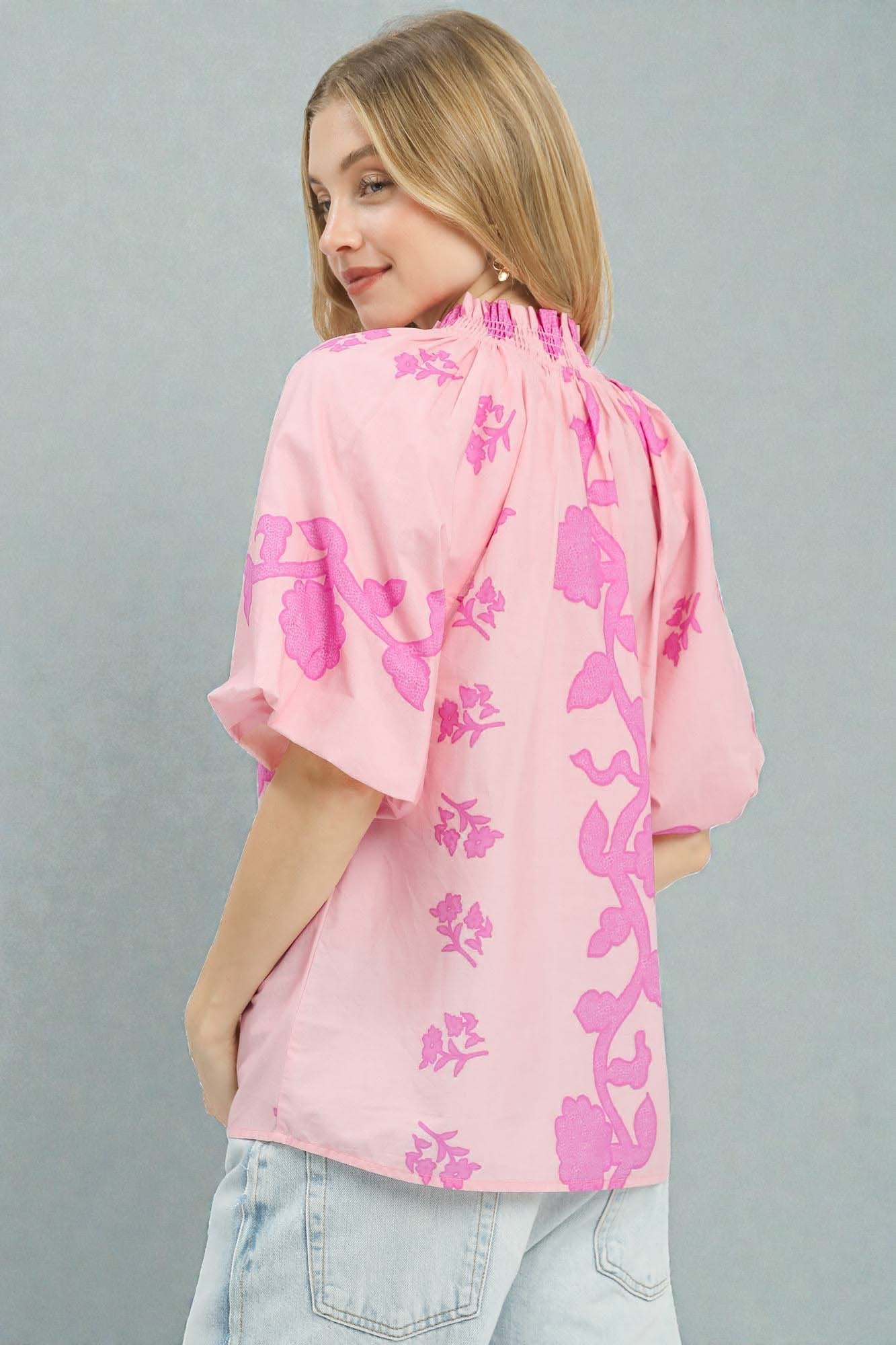 Woman wearing a pink floral kimono-style top against a gray background