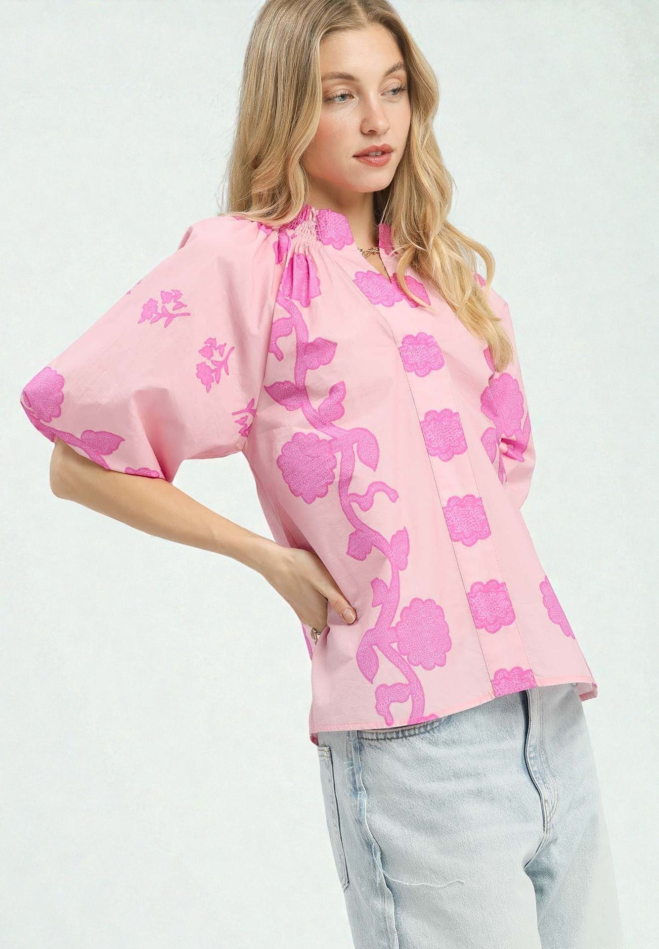 Woman wearing a pink floral blouse with light blue jeans on a white background