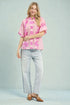 Woman wearing a pink floral blouse and light blue jeans on a gray background