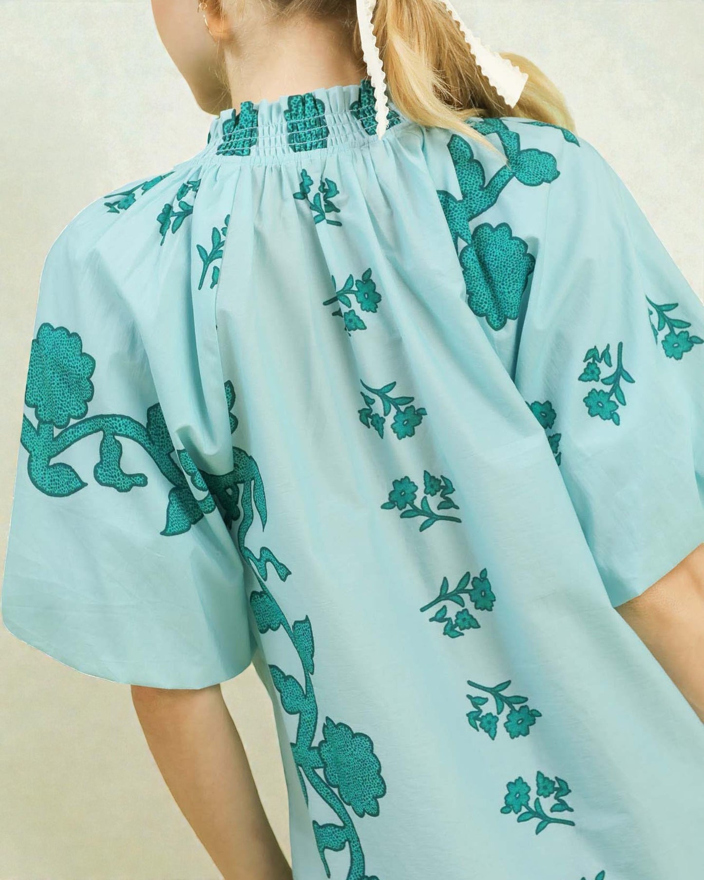 Light blue dress with green floral embroidery on a plain background