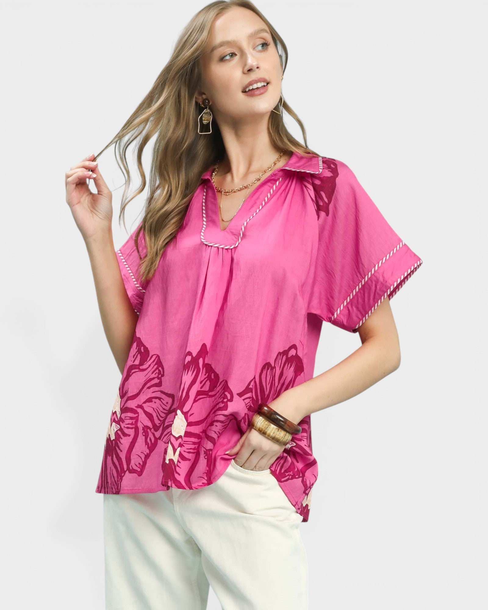 Woman wearing a pink blouse with floral patterns on a white background