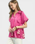 Woman wearing a pink blouse with floral patterns on a white background