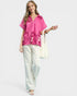 Woman wearing a pink floral blouse and white pants on a white background