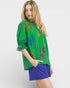 Woman wearing a green floral embroidered top with blue shorts on a white background