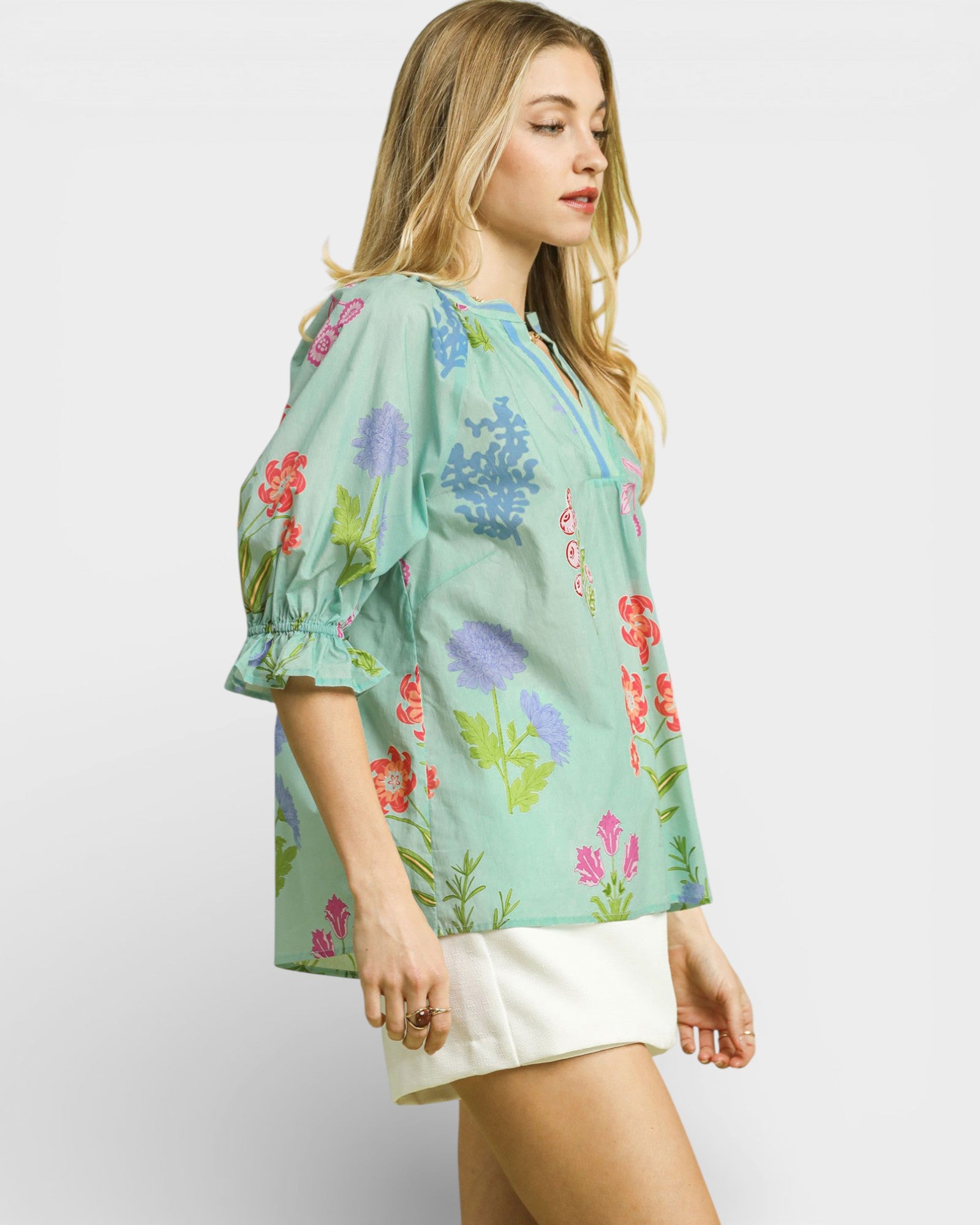 Woman wearing a light green floral blouse against a white background