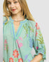 Woman wearing a light blue dress with floral embroidery on a plain background