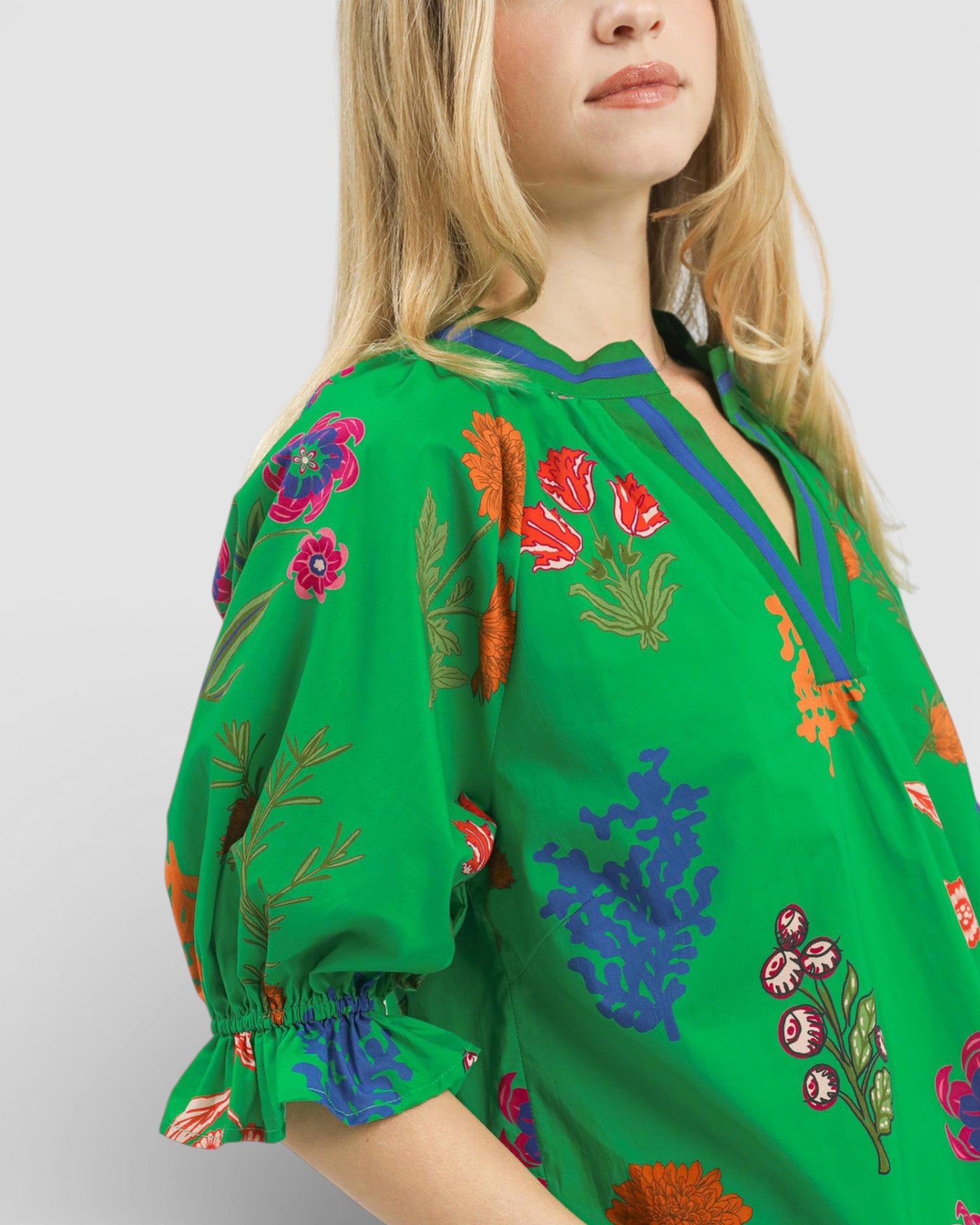 Green embroidered blouse with colorful floral patterns on a white background