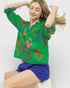 Woman wearing a green embroidered blouse with colorful floral patterns on a white background