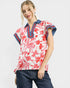 Woman wearing a red floral blouse with blue accents on a white background