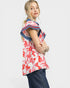 Woman wearing a red and white floral top with blue accents on a white background