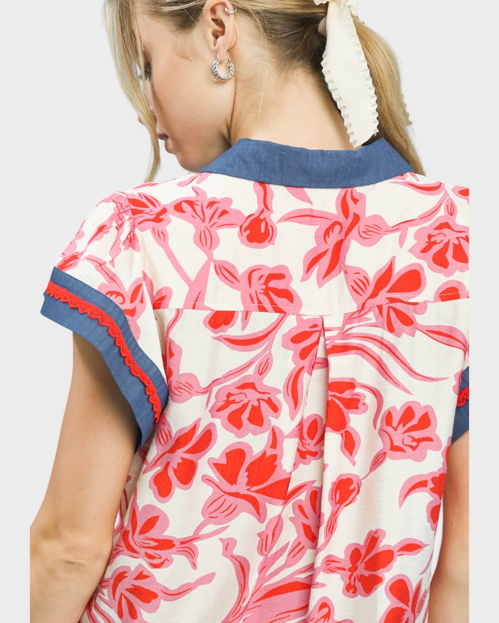 Person wearing a floral dress with red and blue accents on a plain background