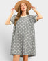 Woman wearing a gray floral dress and beige hat on a light gray background