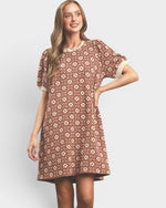 Woman wearing a patterned dress on a plain background