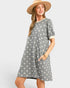 Woman wearing a gray floral dress and beige hat on a white background