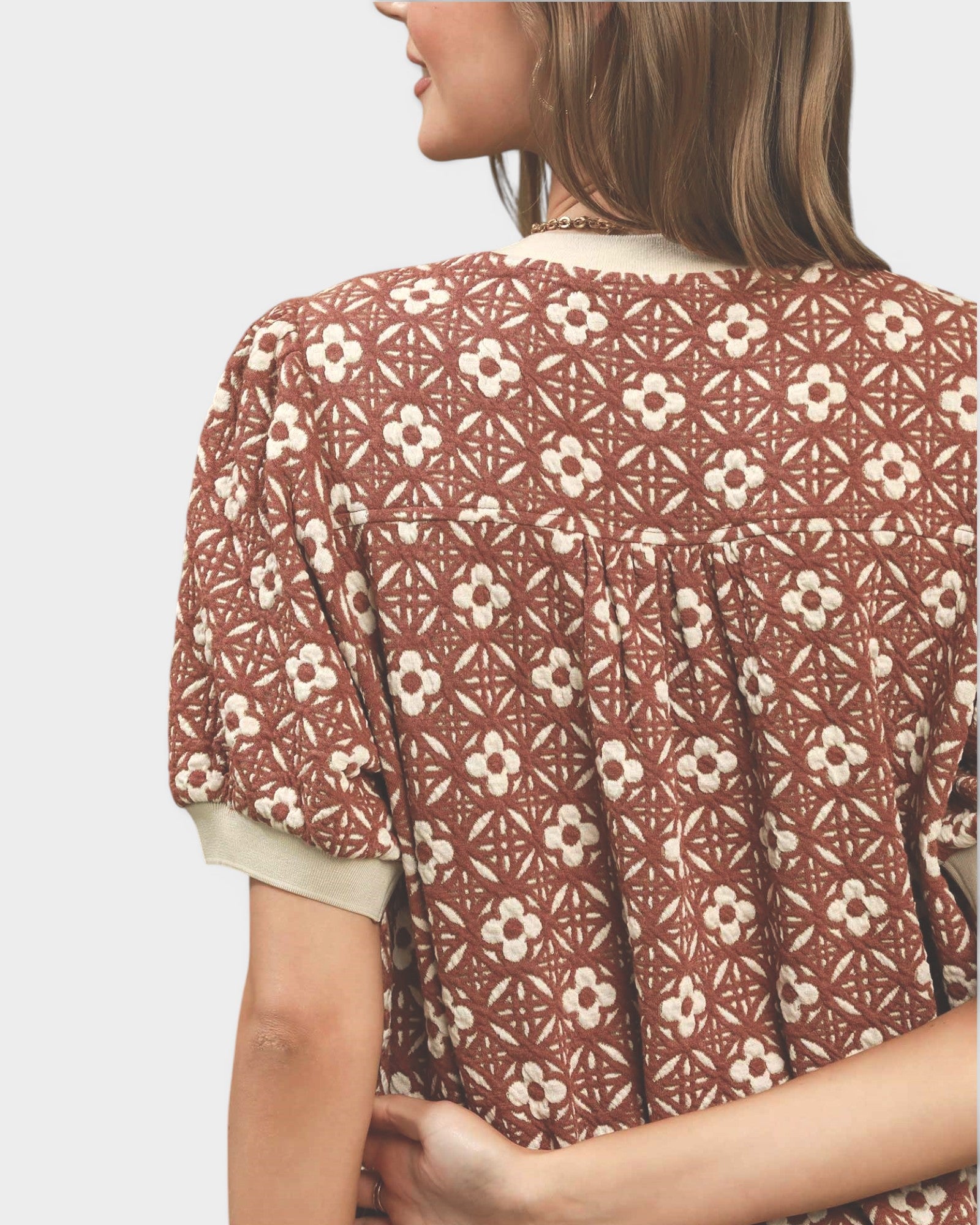 Woman wearing a patterned blouse with a neutral background